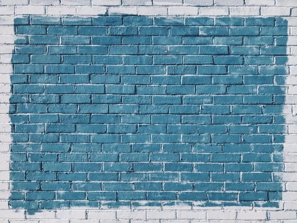 A white brick wall with a large patch freshly painted blue